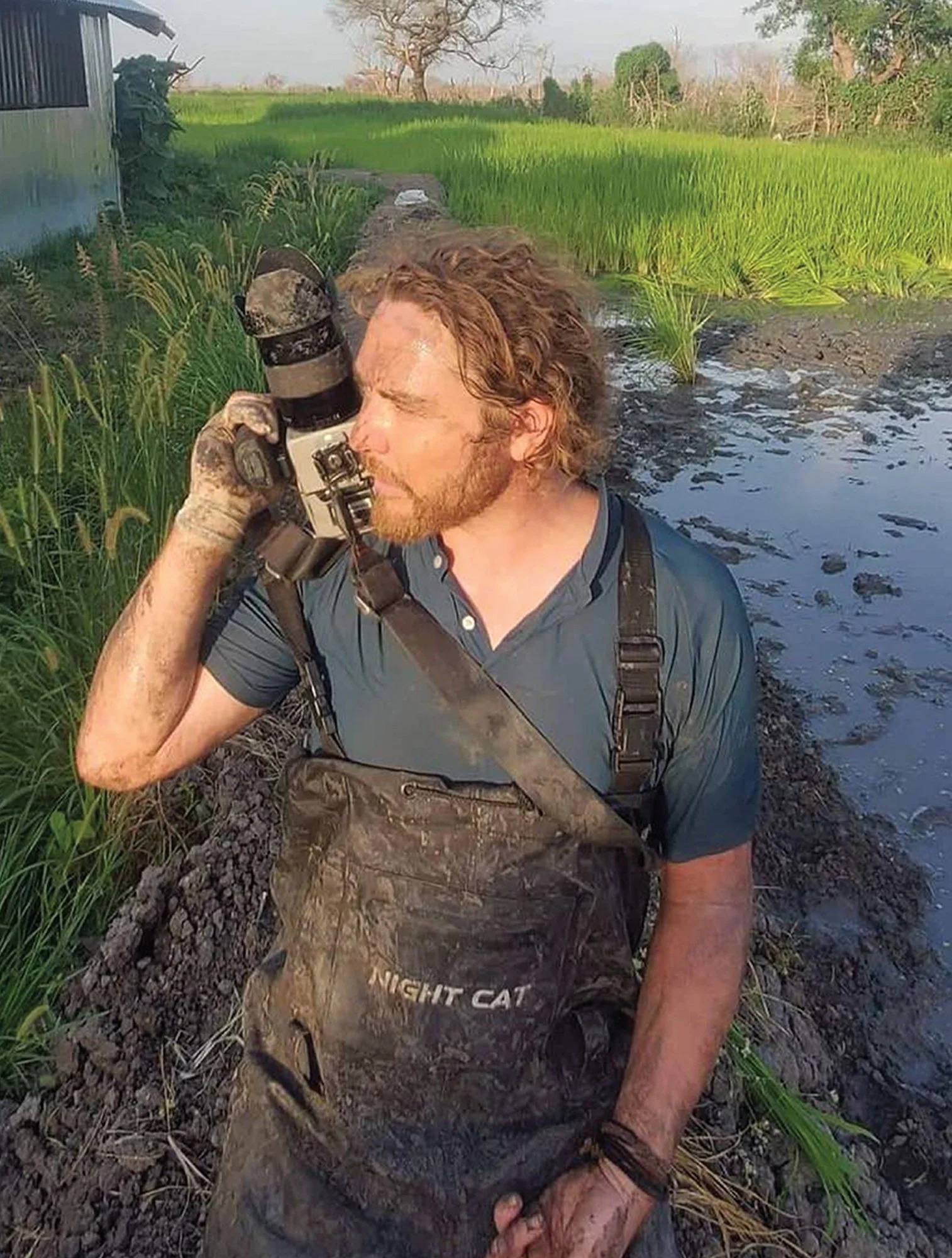 Image of photographer in muddy overalls.