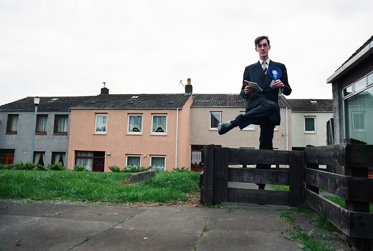 Photographer's image of politician Jacob Rees-Mogg stepping over a gate after leaving a property on the campaign trail.