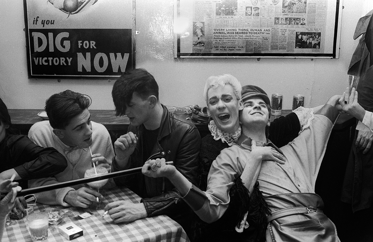 pedwar dyn ifanc o amgylch bwrdd yng Nghlwb y Blitz. Llundain, 1980au
