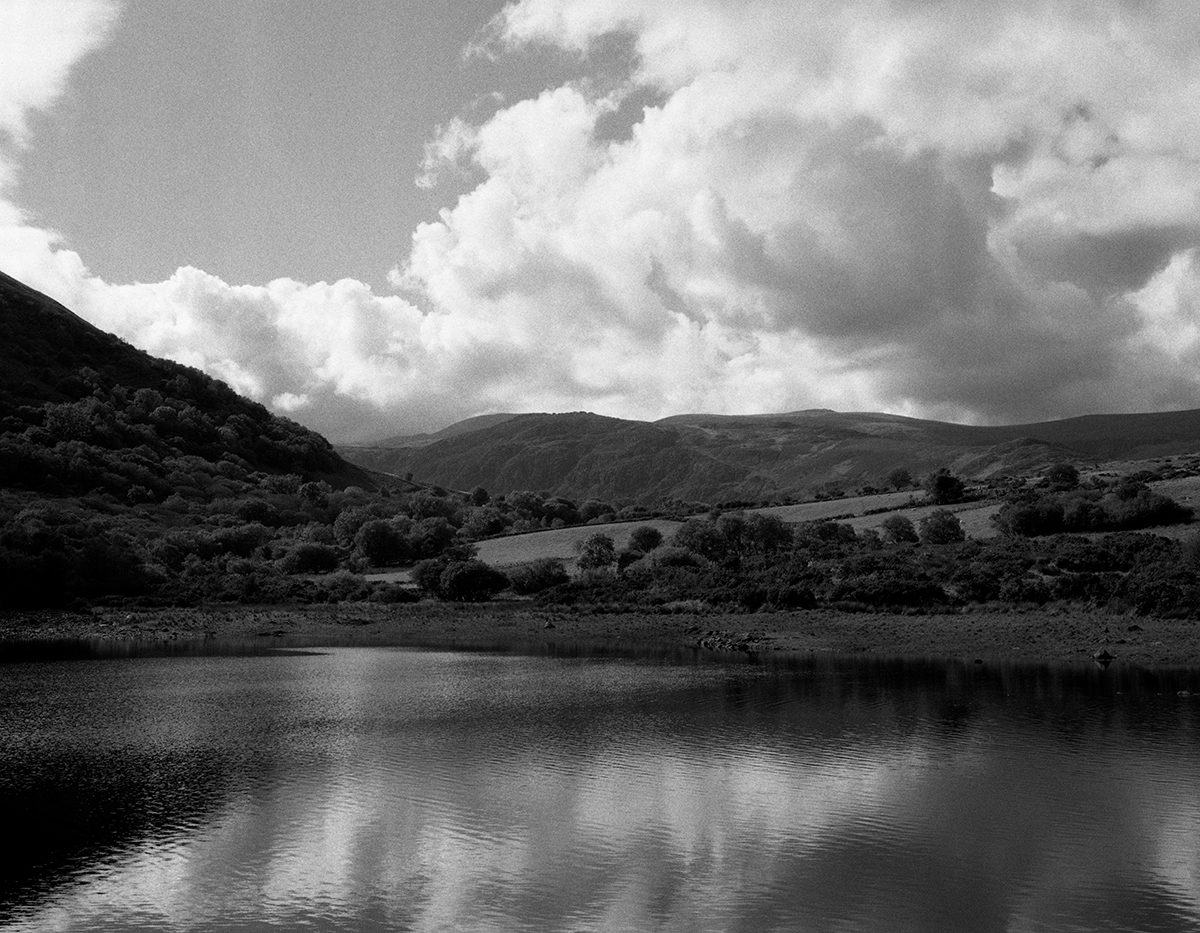 Landscape photograph by photographer showing mountains and lake in black and white.