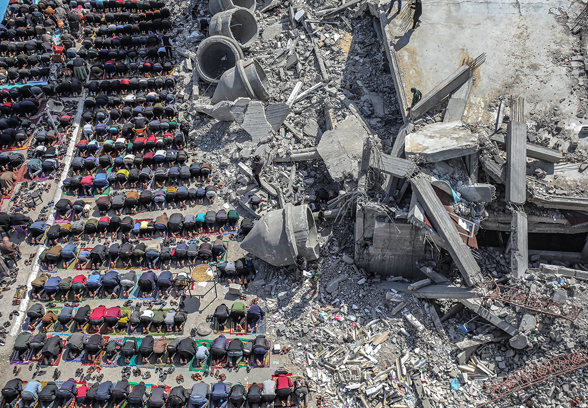 people praying on their knees in a war torn city